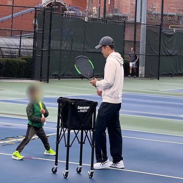 Richard coaching a young player on an outdoor court